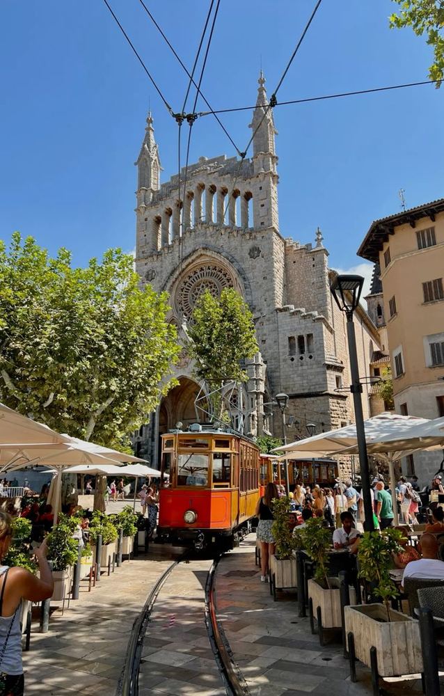 The orange vintage tram in front of Sóller church