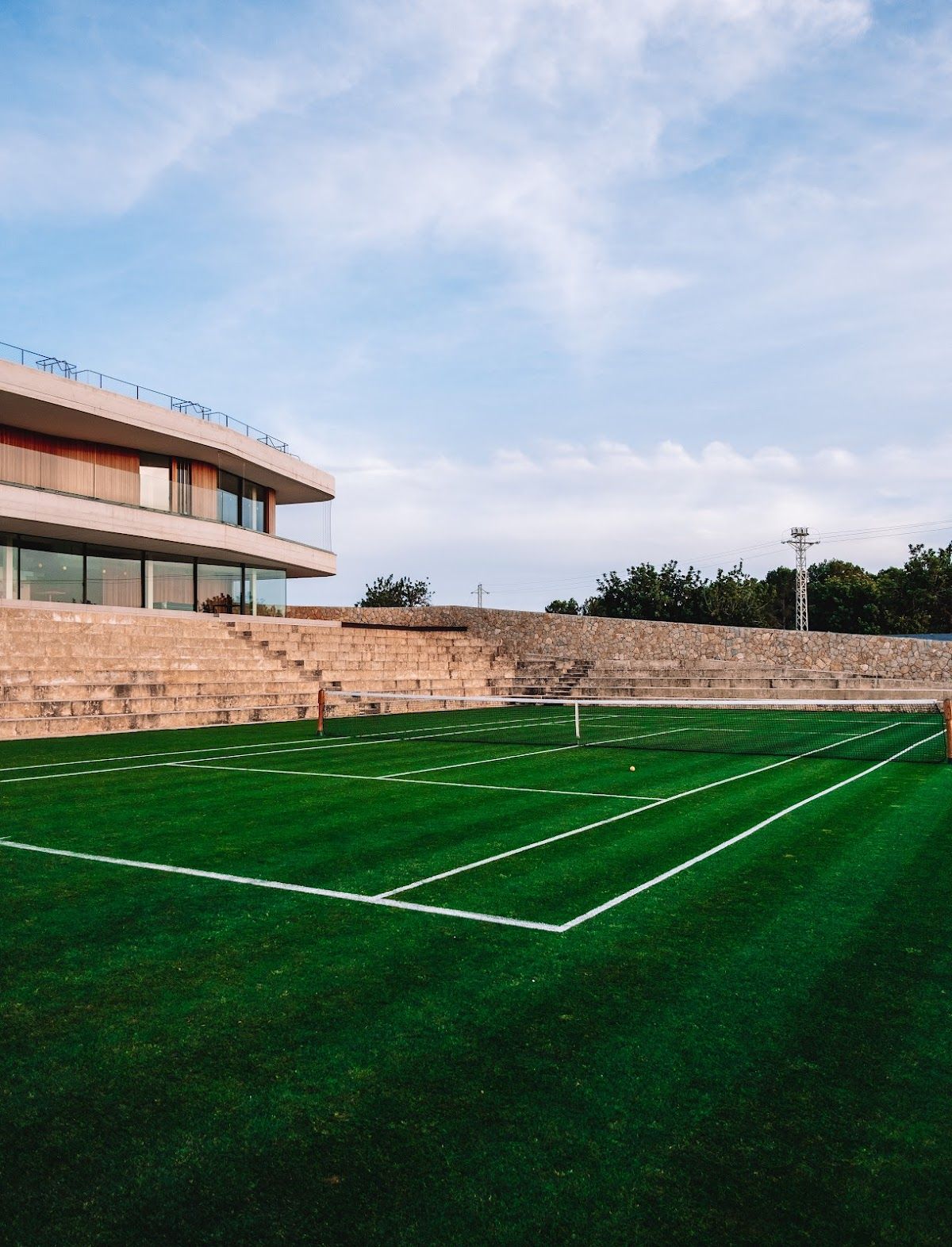 A grass tennis court beside the clubhouse