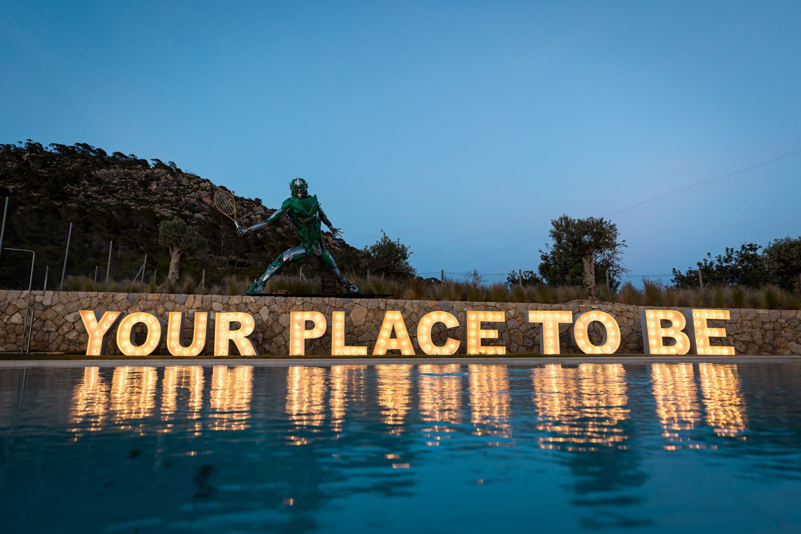 Illuminated YOUR PLACE TO BE letters reflected in the pool