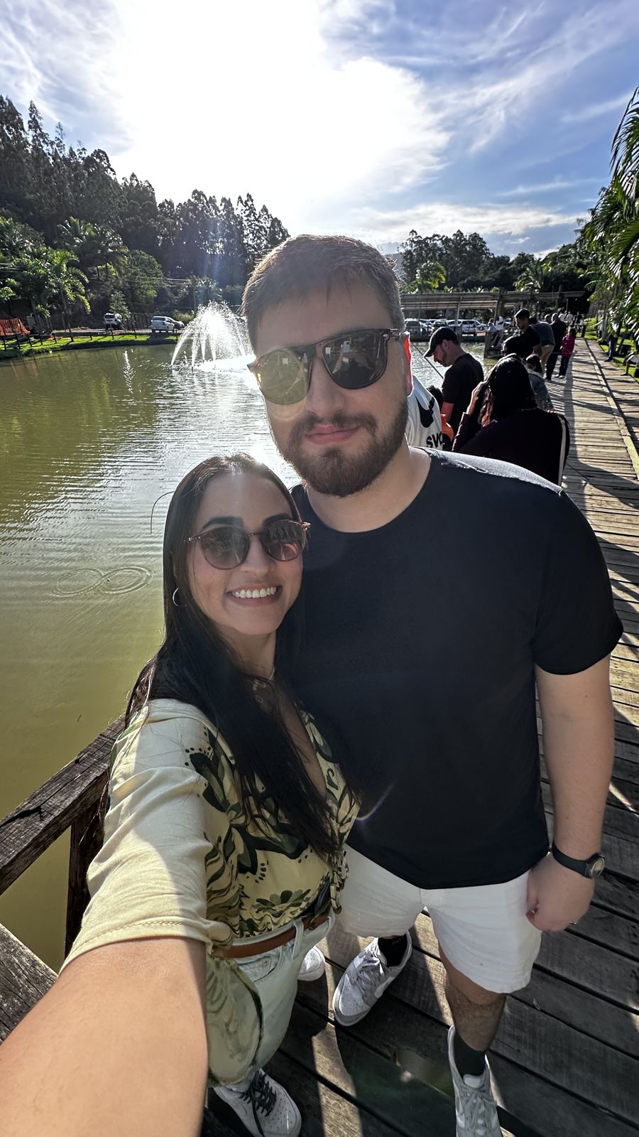 A selfie of the couple by a lake with a fountain