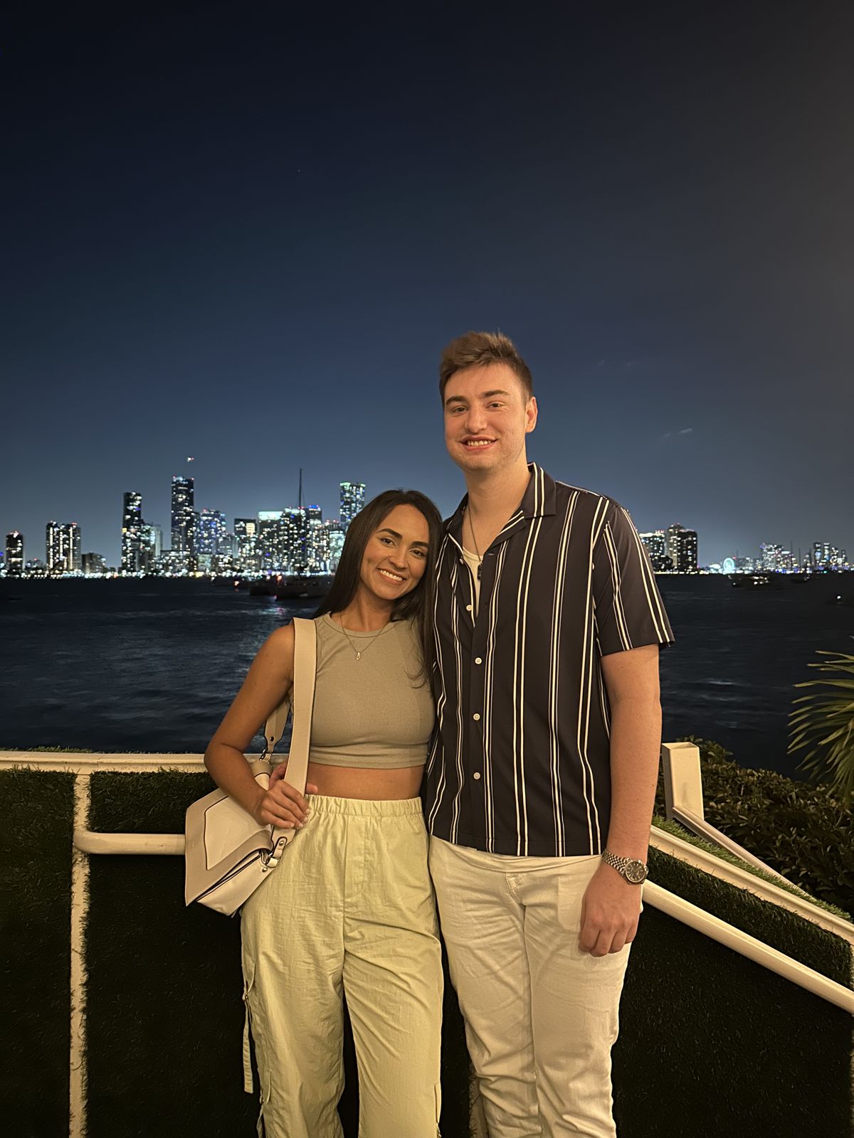 The couple at night with a city skyline behind them