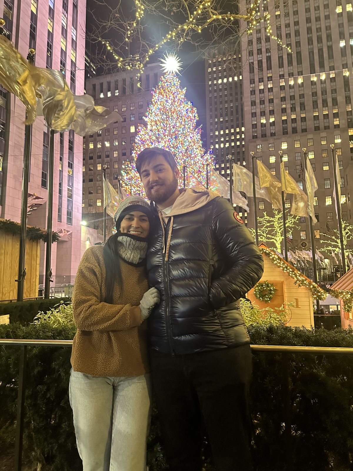 The couple in front of a giant Christmas tree