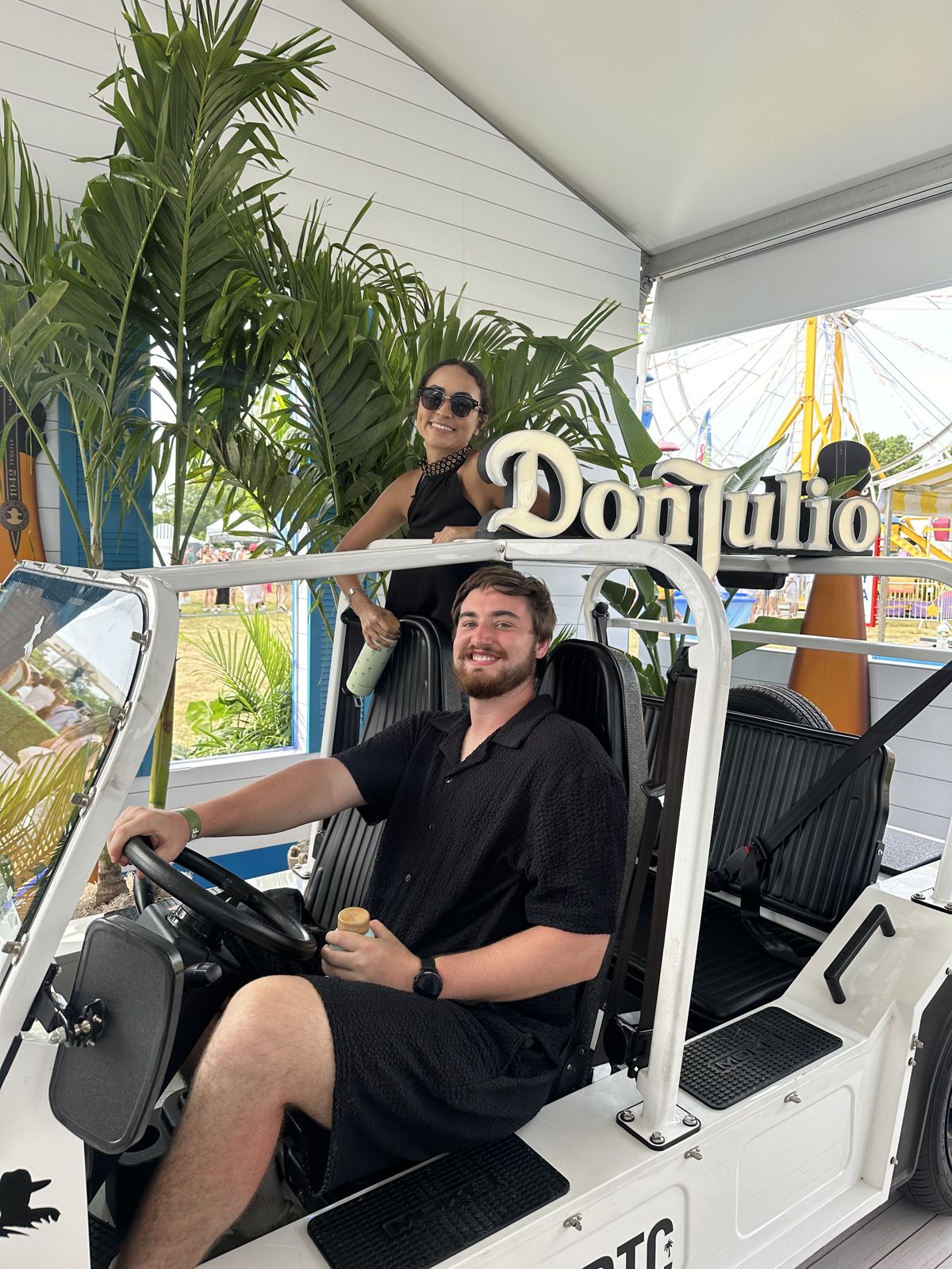 Patrick driving a small cart while Jessica stands behind him
