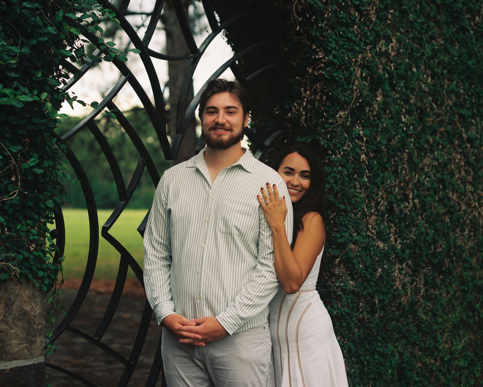 The couple by an iron garden gate covered in ivy