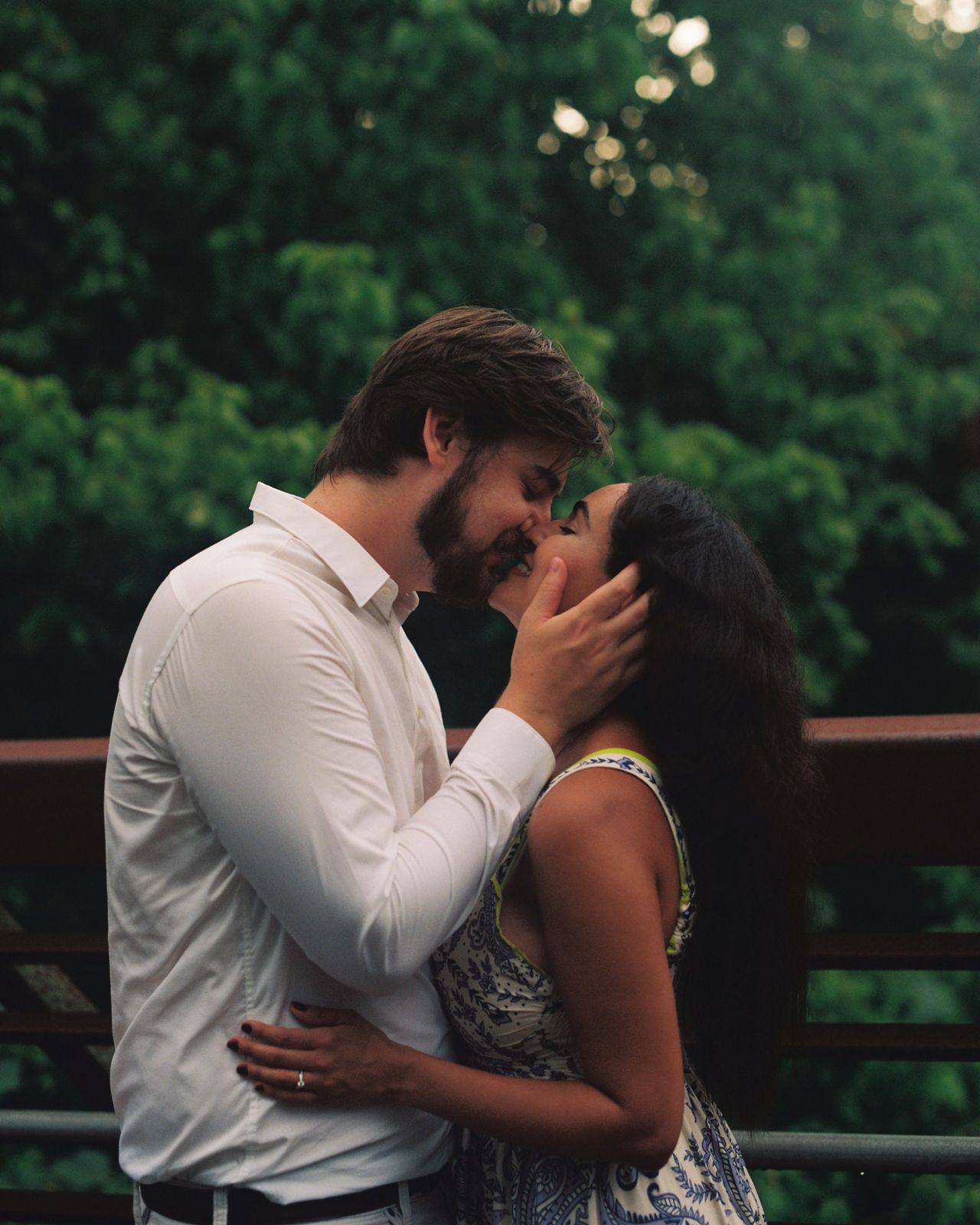 Jessica and Patrick kissing in front of a leafy background